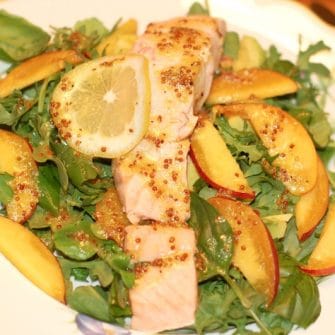 poached salmon and peaches on top of a bed of arugula