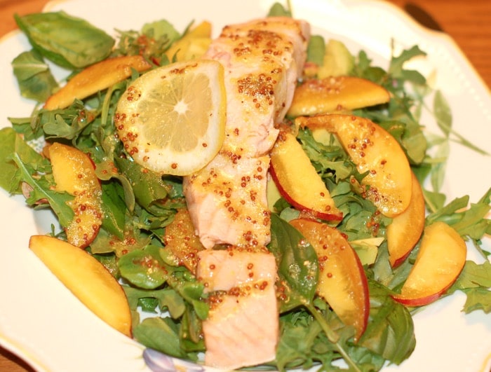 poached salmon and peaches on top of a bed of arugula