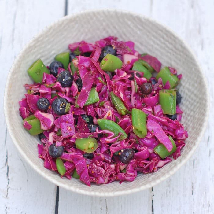 This colorful red cabbage blueberry salad is quick and easy to make, pretty to look at, and filled with health-enhancing nutrients. Enjoy it at your next summer social gathering! Recipe via JessicaLevinson.com | #cabbage #blueberries #slaw #salad #glutenfree #dairyfree #vegan #vegetarian