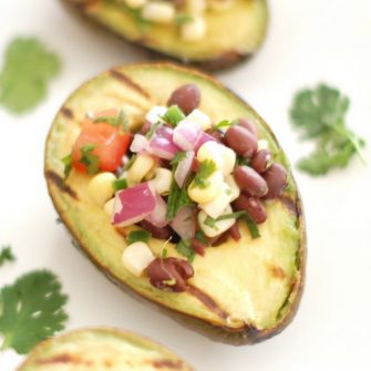 Grilled avocados are stuffed with a light and fresh mixture of corn, black beans, and tomatoes in this elegant yet simple appetizer, side dish, or entrée. Get the gluten-free and vegan recipe @jlevinsonrd.
