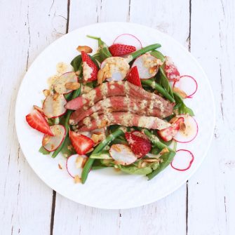 Umami-rich grilled flank steak tops a bed of baby spinach, crisp green beans, and sweet strawberries in this light summer steak salad drizzled with a sparkling, tangy Champagne shallot vinaigrette. via JessicaLevinson.com