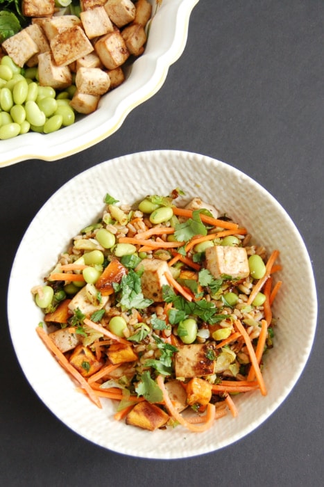 Whole grain farro is topped with shredded carrots, edamame, roasted Brussels sprouts sweet potatoes, and crispy baked tofu. Tossed with a miso lime dressing, this Asian-Style Farro Buddha Bowl is a vegetarian and vegan-friendly meal the whole family will love.