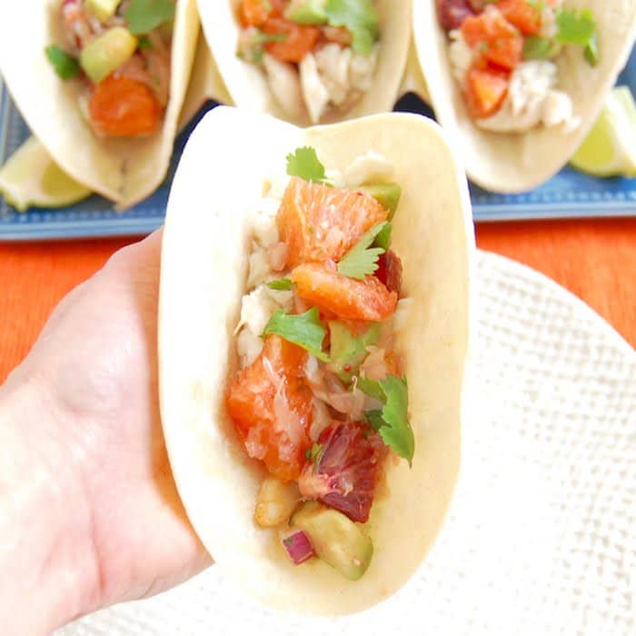 Hand holding Fish Tacos with Citrus Salsa