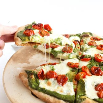 Rosemary-Roasted Tomato Pesto Pizza | Whole wheat crust is topped with a nut-free kale pesto lightened up with ricotta cheese, rosemary-roasted tomatoes, and fresh mozzarella cheese. A delicious and healthier way to enjoy pizza night at home. Get the vegetarian and nut-free recipe @jlevinsonrd.