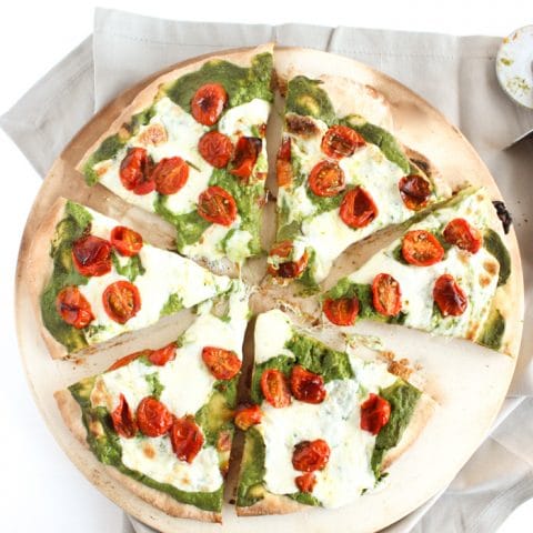 Rosemary-Roasted Tomato Pesto Pizza | Whole wheat crust is topped with a nut-free kale pesto lightened up with ricotta cheese, rosemary-roasted tomatoes, and fresh mozzarella cheese. A delicious and healthier way to enjoy pizza night at home. Get the vegetarian and nut-free recipe @jlevinsonrd.