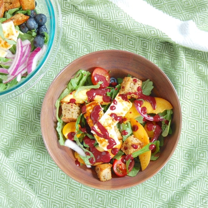 bowl of peach panzanella salad tossed with blueberry balsamic salad dressing