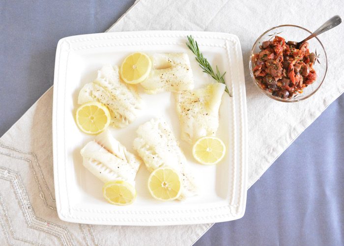 Oven Baked Cod with lemon on plate and side of olive tapenade