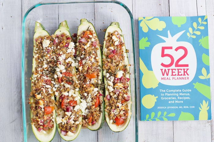 lentil stuffed zucchini boats in glass baking dish next to meal planner book