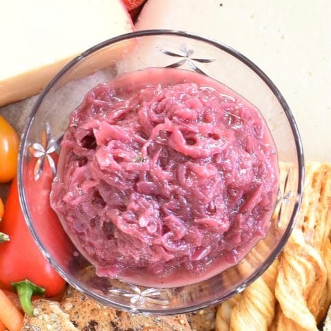 Reduced added sugar red onion jam is a delicious addition to an appetizer board with cheese, crackers, and vegetables. It can also be enjoyed on sandwiches, tossed in salads, or on chicken and beef.