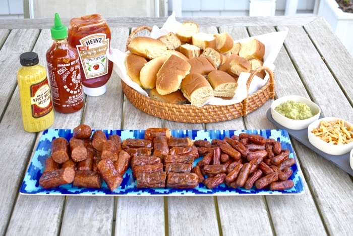 hot dog and sausage slider bar with all the fixings on picnic table