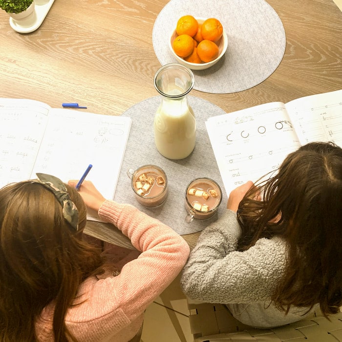 overhead image of children doing homework with hot chocolate